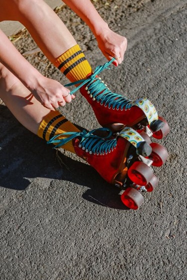 Hands lace a brightly coloured pair of roller-skates.