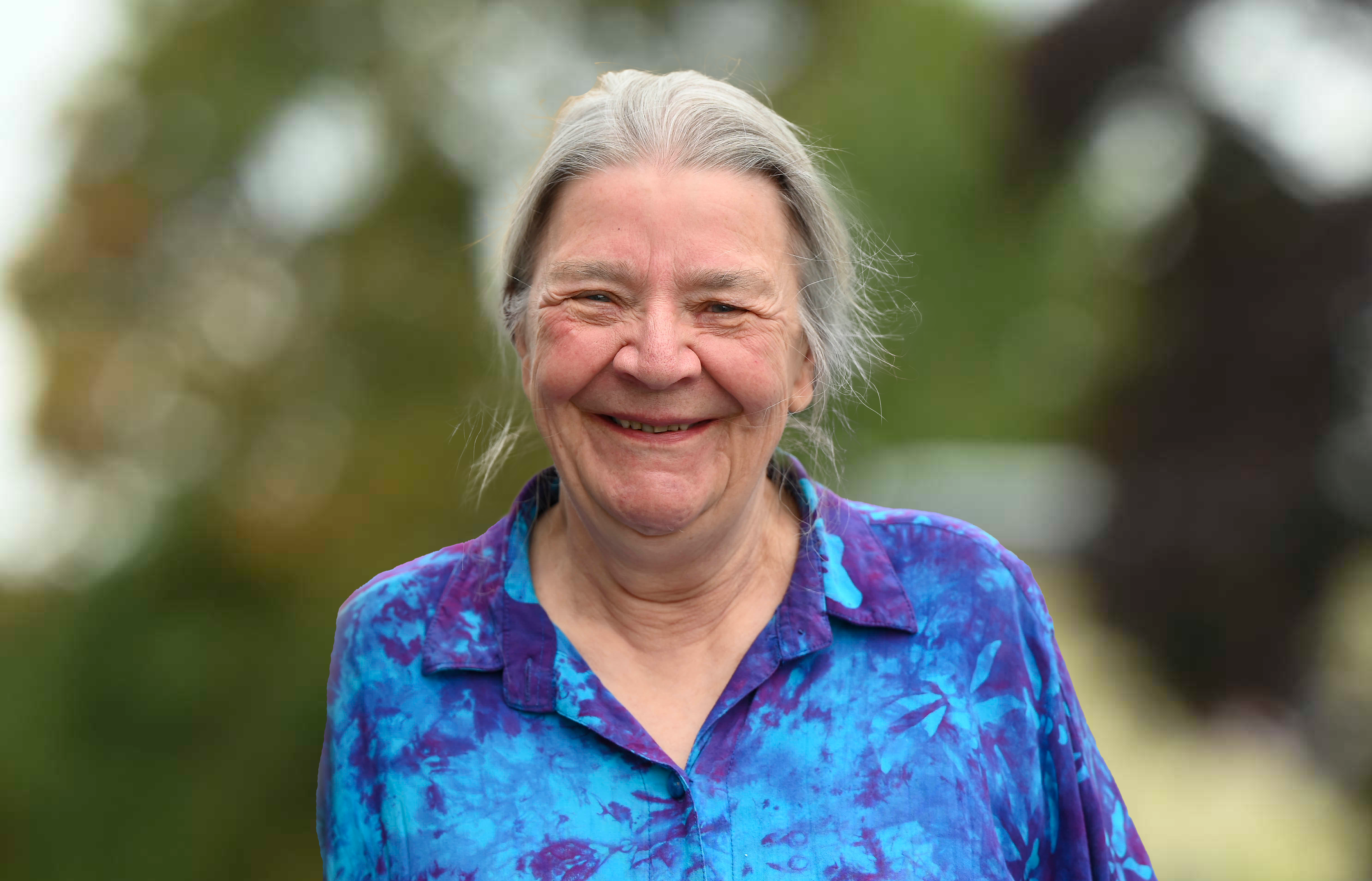 Older woman in a blue shirt smiles.