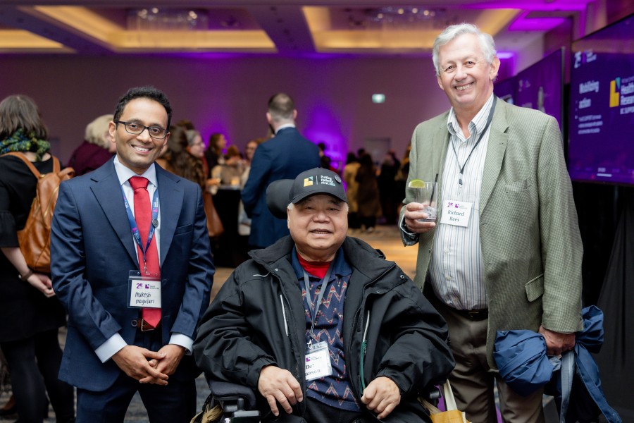A group of three smiling attendees at the 25th Anniversary event on March 2, 2026.