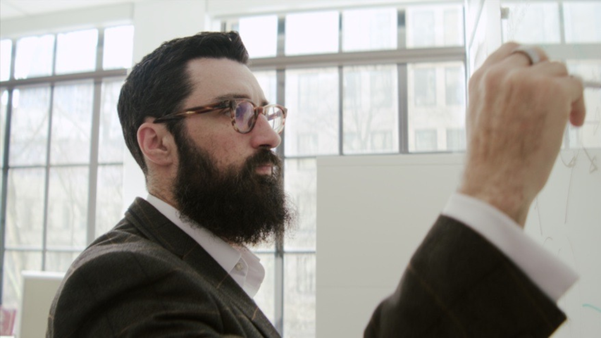 Image of Dr. Theodore Cosco writing on white board.