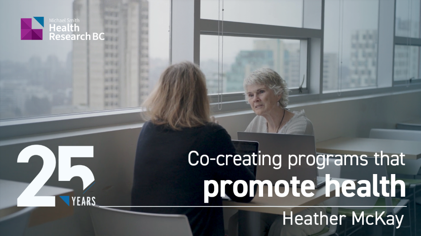 Two individuals are seated at a table with laptops in a well-lit room overlooking a cityscape. The image features text: "25 Years" and "Co-creating programs that promote health - Heather McKay." The logo for Michael Smith Health Research BC is visible in the top left corner.